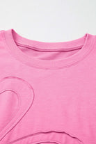 Close-up of Flower Theory Top in taffy pink with oversized floral design and ribbed neckline.