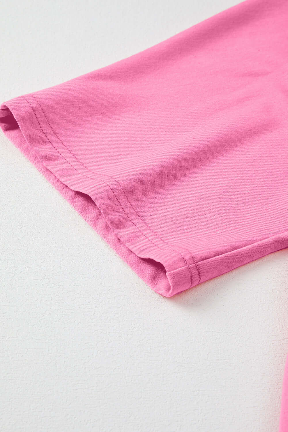 Close-up of the sleeve hem of a pink taffy Flower Theory Top, showcasing soft knit fabric and relaxed fit.