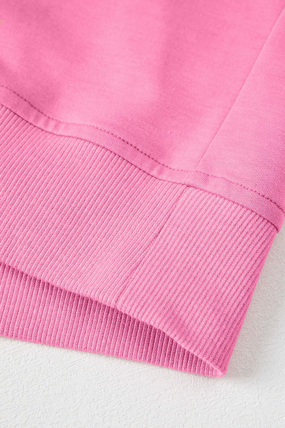Close-up of the ribbed hem of the taffy pink Flower Theory Top, showcasing its comfortable fabric texture.
