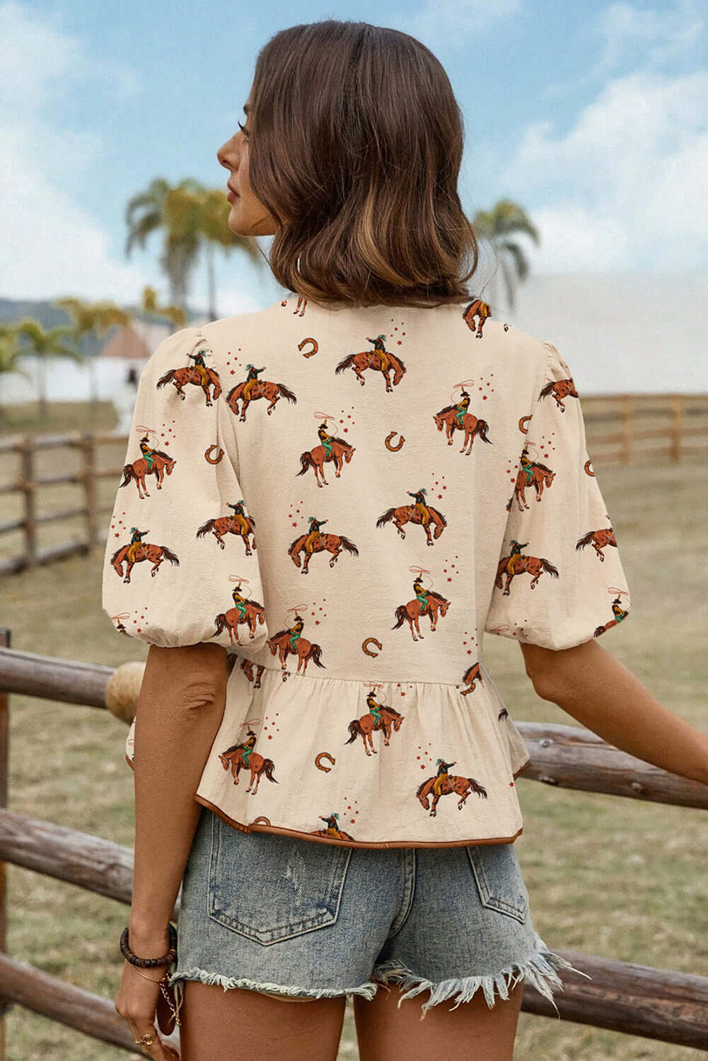 Back view of the Rodeo Romance Top with cowboy and horseshoe print, featuring puff sleeves and a peplum style.