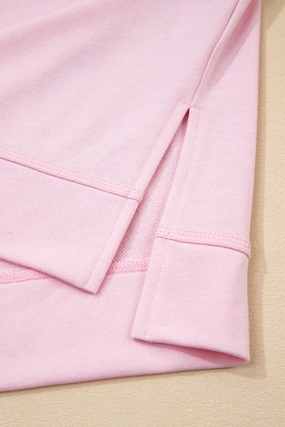 Detail of the SWEET ESCAPE TOP showing the soft pink fabric and stylish hemline design.