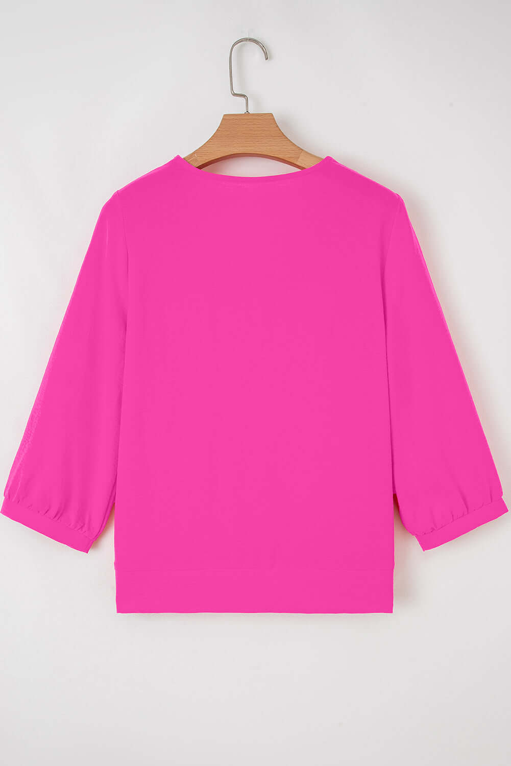 Back view of the GRACEFUL GLOW TOP (bright pink) showcasing its vibrant color and bracelet sleeves.