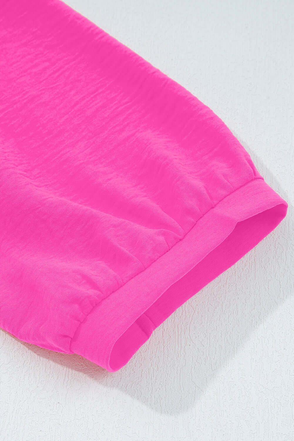 Bright pink sleeve detail of the GRACEFUL GLOW TOP (bright pink) showcasing its crinkled fabric texture.