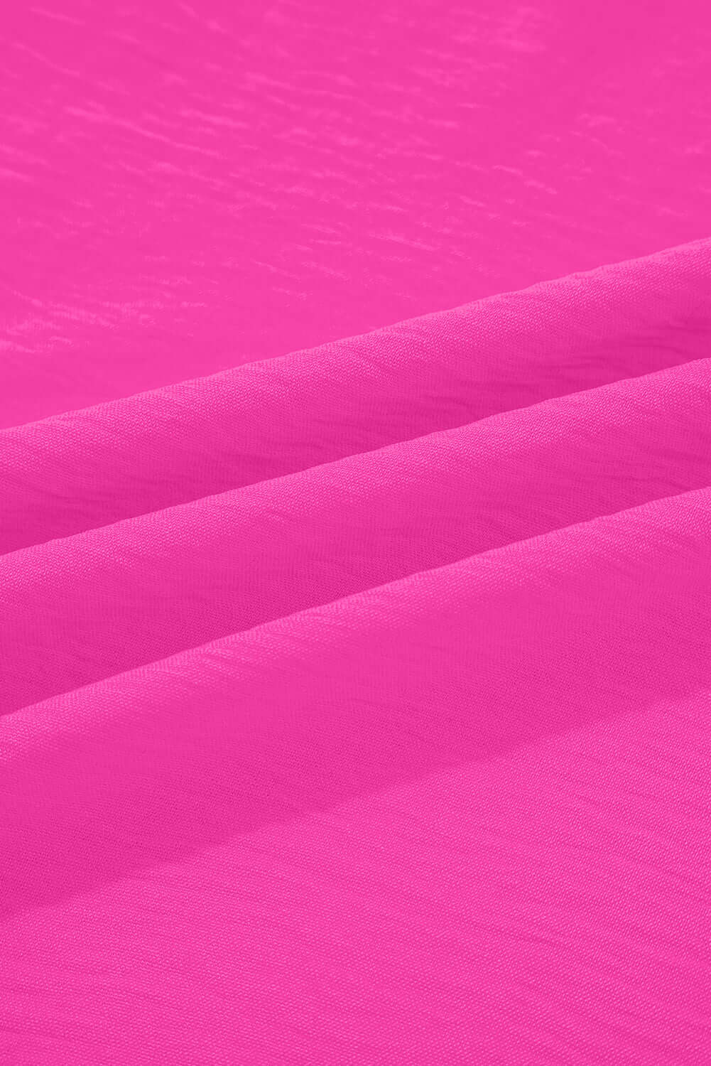 Close-up of vibrant crinkled fabric texture in bright pink for GRACEFUL GLOW TOP (bright pink).