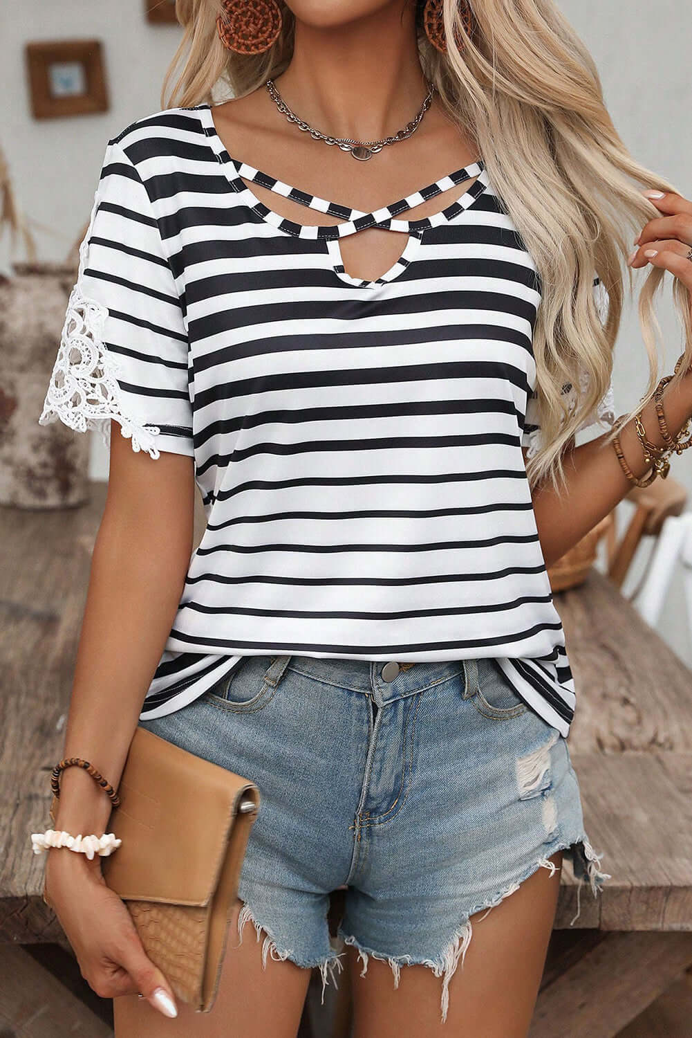 Crisscross Charisma Top with black and white stripes and lace sleeves, styled with denim shorts.