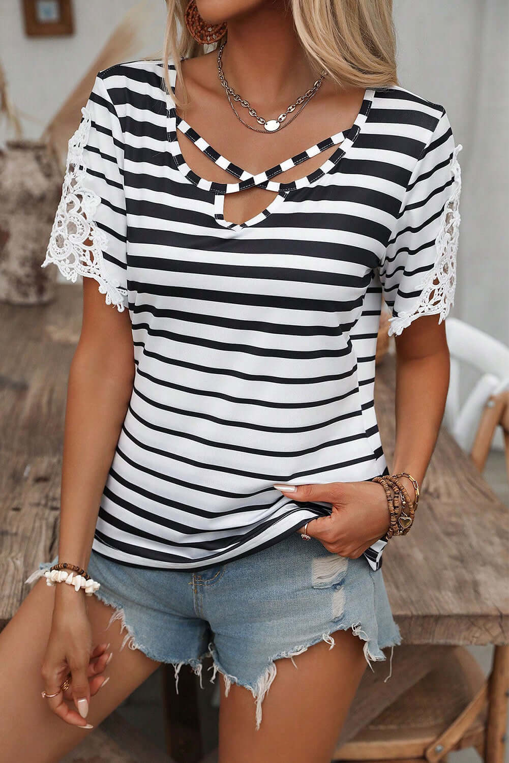Chic black and white striped blouse with crisscross neckline and lace sleeves, perfect for casual summer styling.