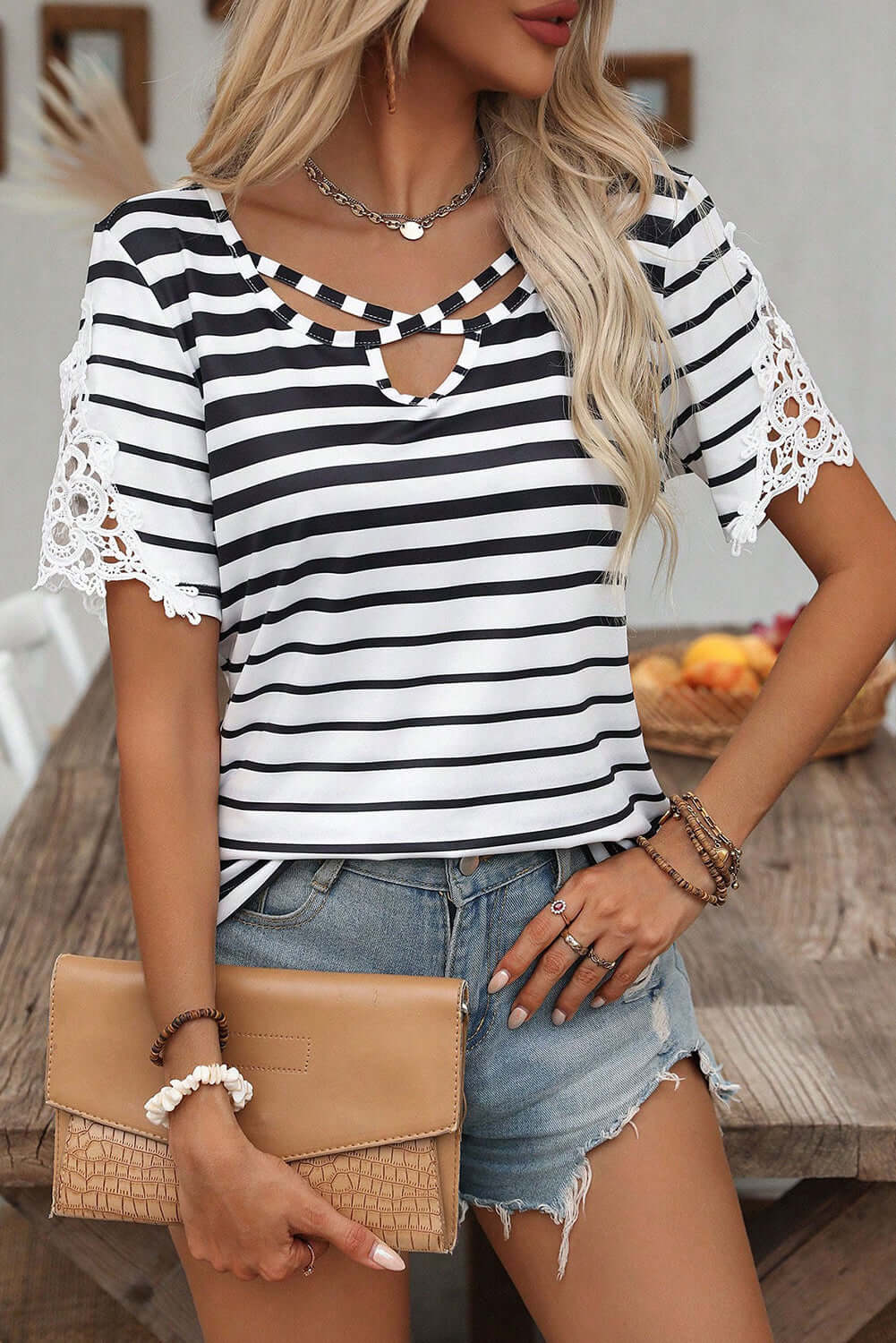 Woman wearing Crisscross Charisma Top with black and white stripes, lace sleeves, and casual style.