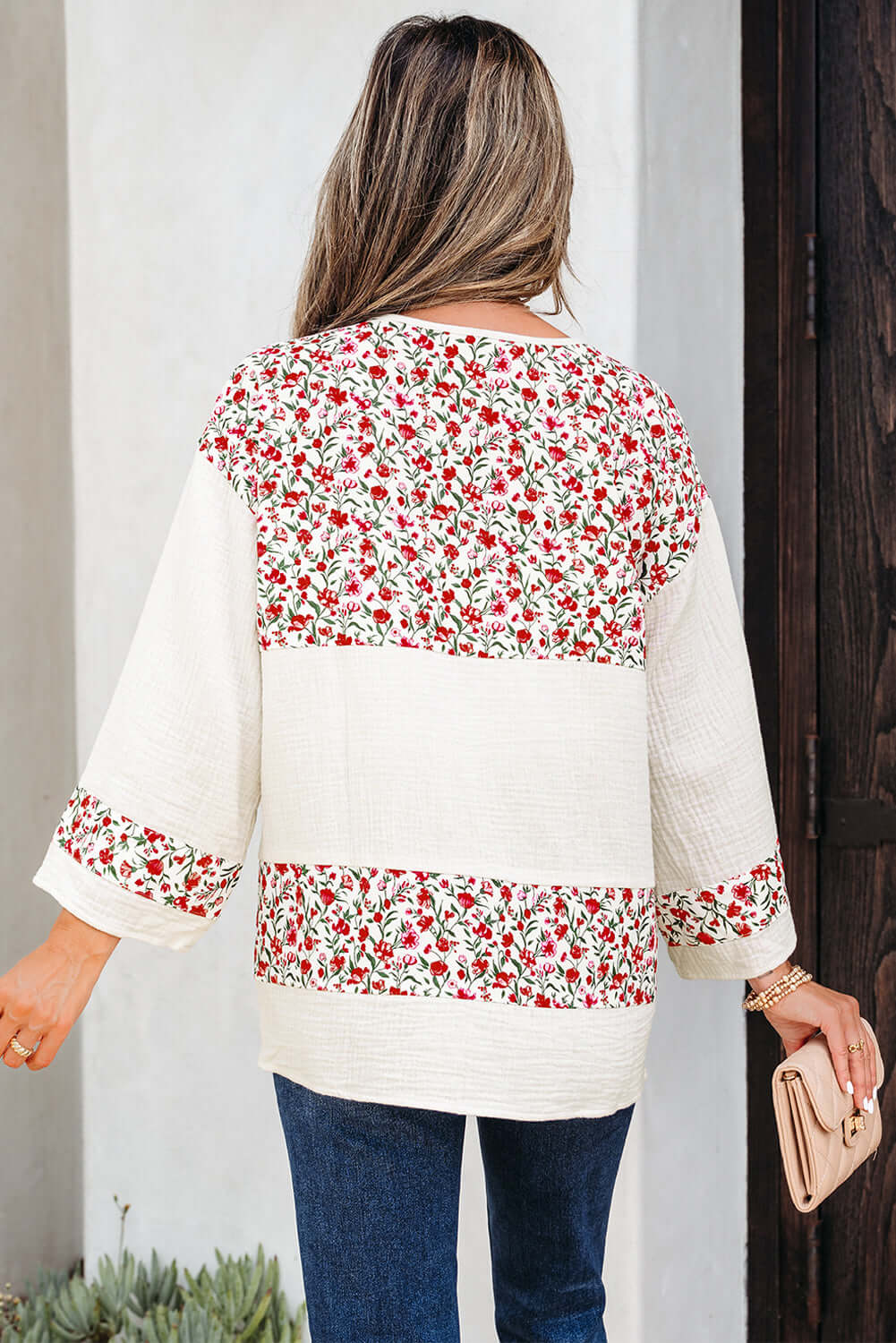 Back view of a woman wearing the CROSSROADS CUTIE blouse with floral patchwork design and 3/4 sleeves.