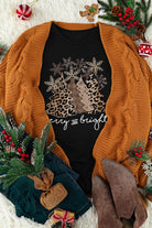 Black Merry & Bright Leopard Tee with Christmas tree graphic, styled with a brown cardigan, festive decor, and boots.