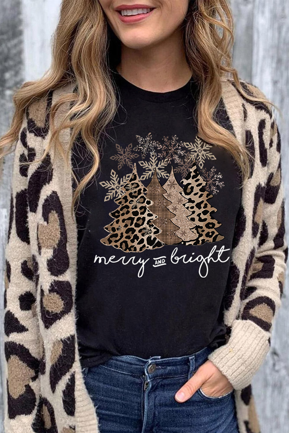 Black tee with leopard print Christmas tree graphic and "Merry & Bright" text, worn by model with a matching cardigan.