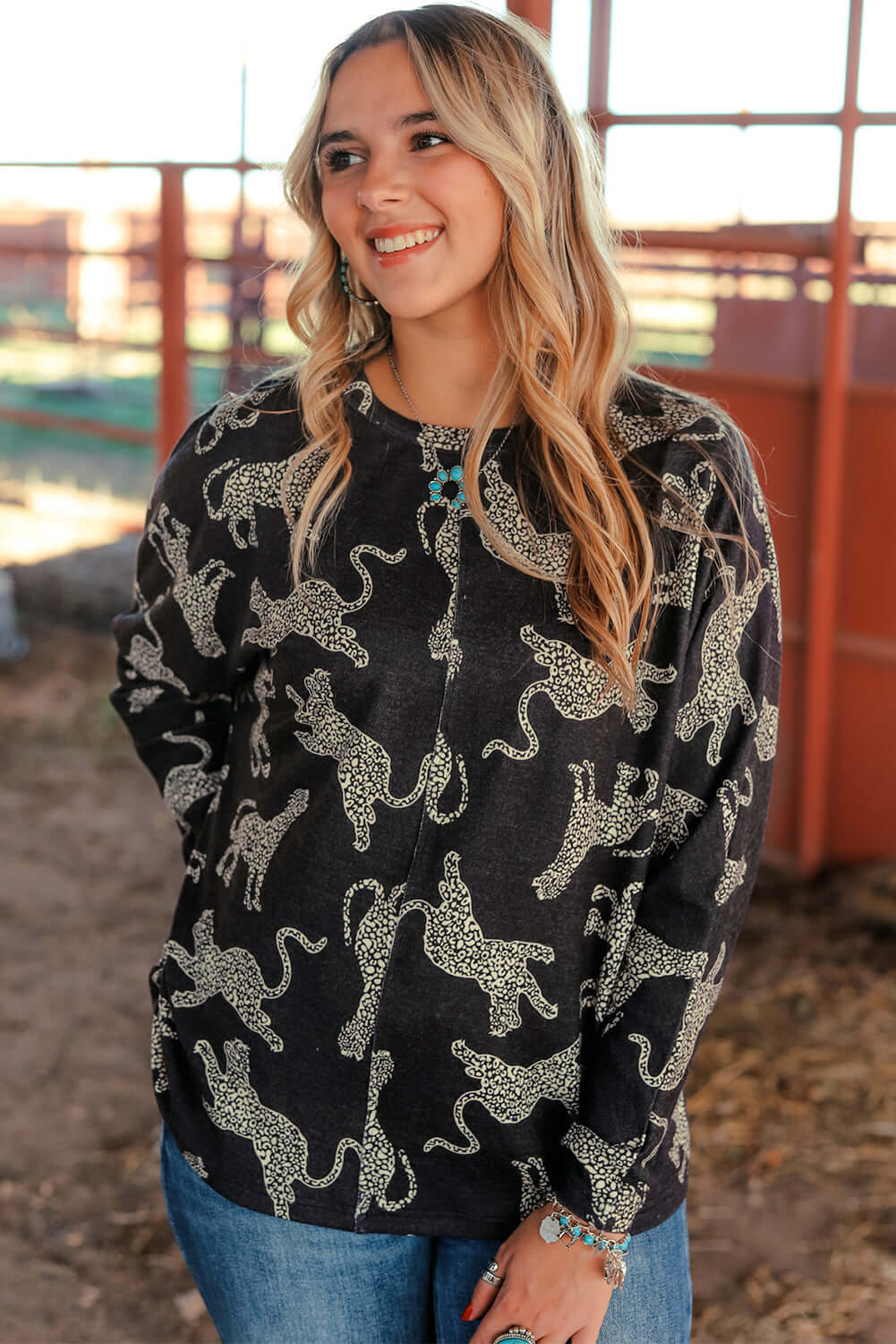 Model wearing the Cant Be Tamed long-sleeved top with cheetah print, styled casually with jeans in a rustic setting.