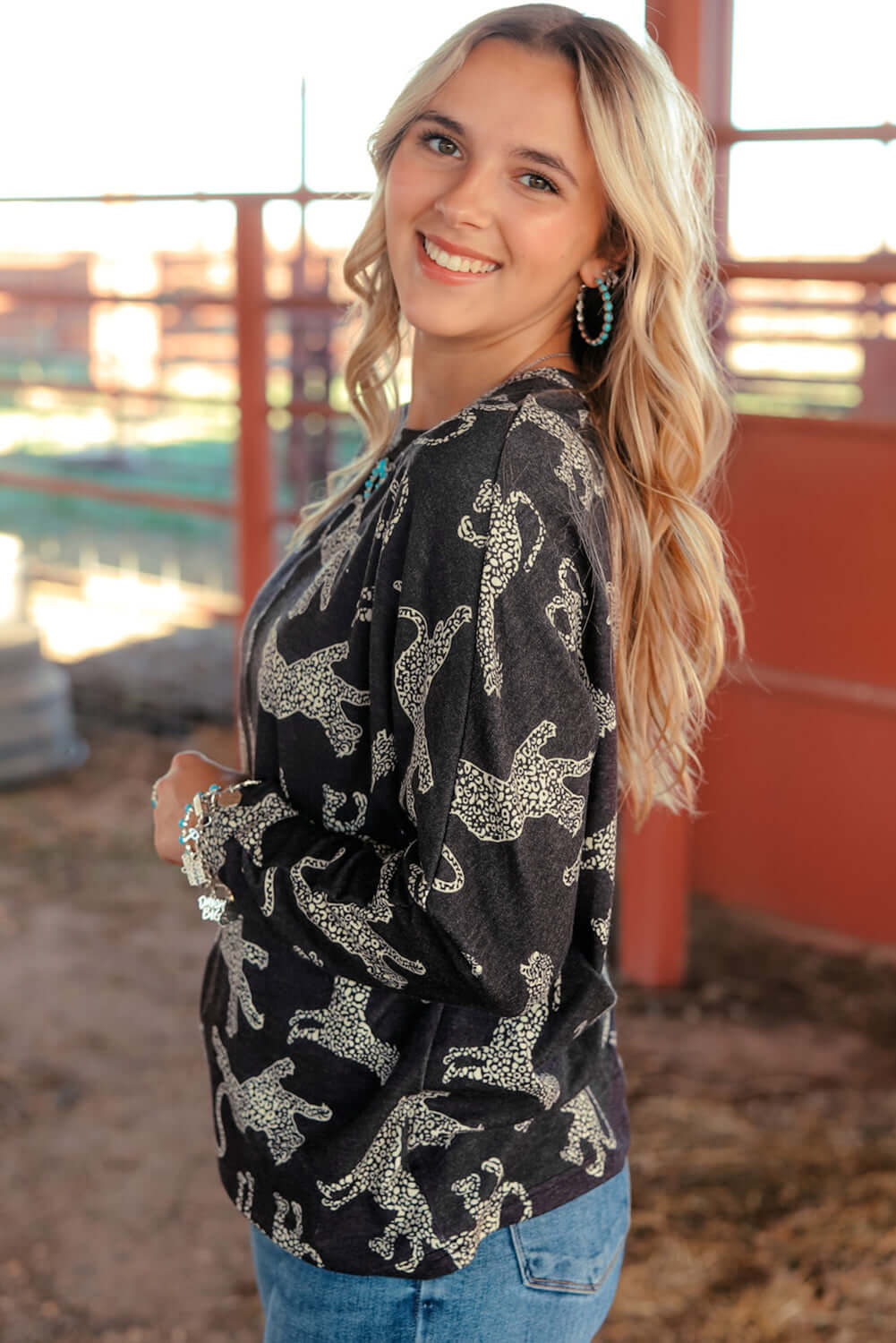 Young woman smiling in a cheetah print long-sleeved top, showcasing a stylish and versatile outfit. Perfect for casual or dressy looks.