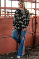 Model showcasing the Cant Be Tamed long-sleeved top with cheetah print, paired with jeans in a rustic setting.