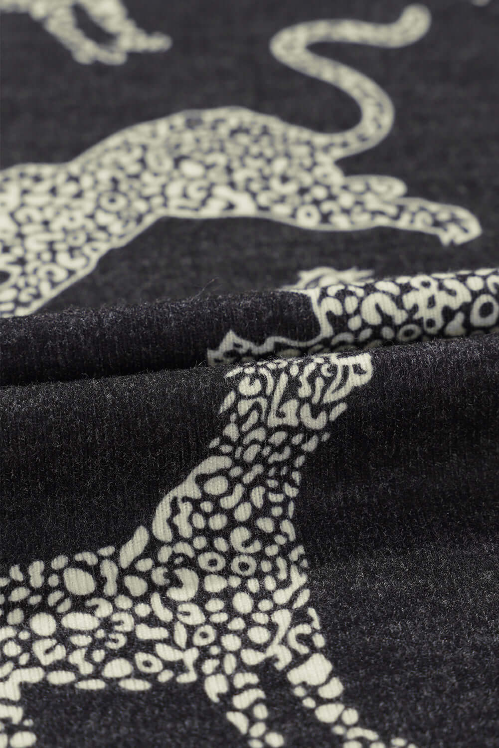 Close-up of soft fabric featuring a bold cheetah print pattern in black and white, ideal for the Cant Be Tamed long-sleeved top.