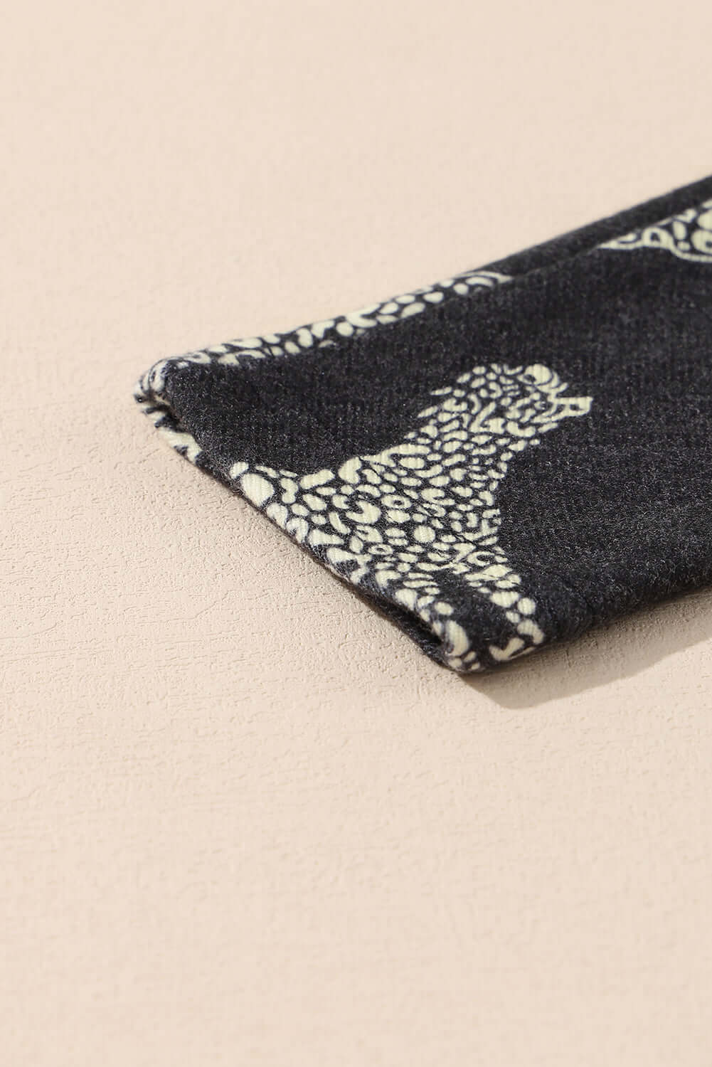 Close-up of the cheetah print fabric of the Cant Be Tamed long-sleeved top on a light background.