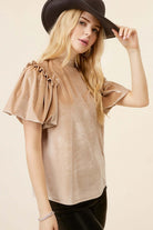 Champagne velvet blouse with ruffled puff sleeves and mock neck, modeled with a black hat for a stylish evening look.