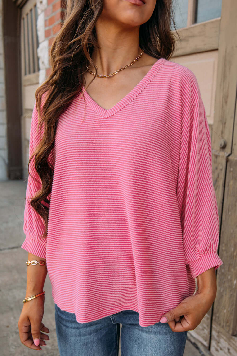 Woman wearing a ribbed pink v-neck top with bracelet sleeves, perfect for casual occasions.