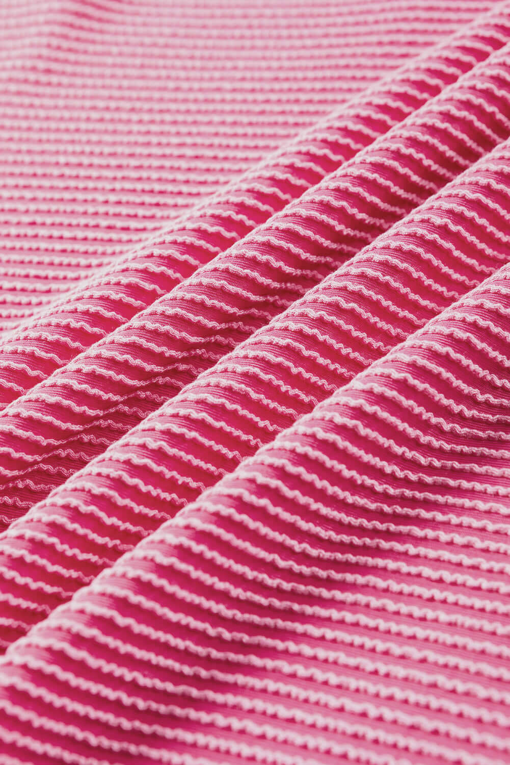 Close-up of soft pink striped fabric showcasing a ribbed texture, perfect for stylish casual wear.