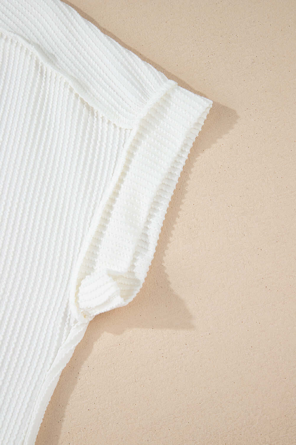 Close-up of the VANILLA VIBE ribbed top showcasing its soft ivory texture and exposed seam stitching.