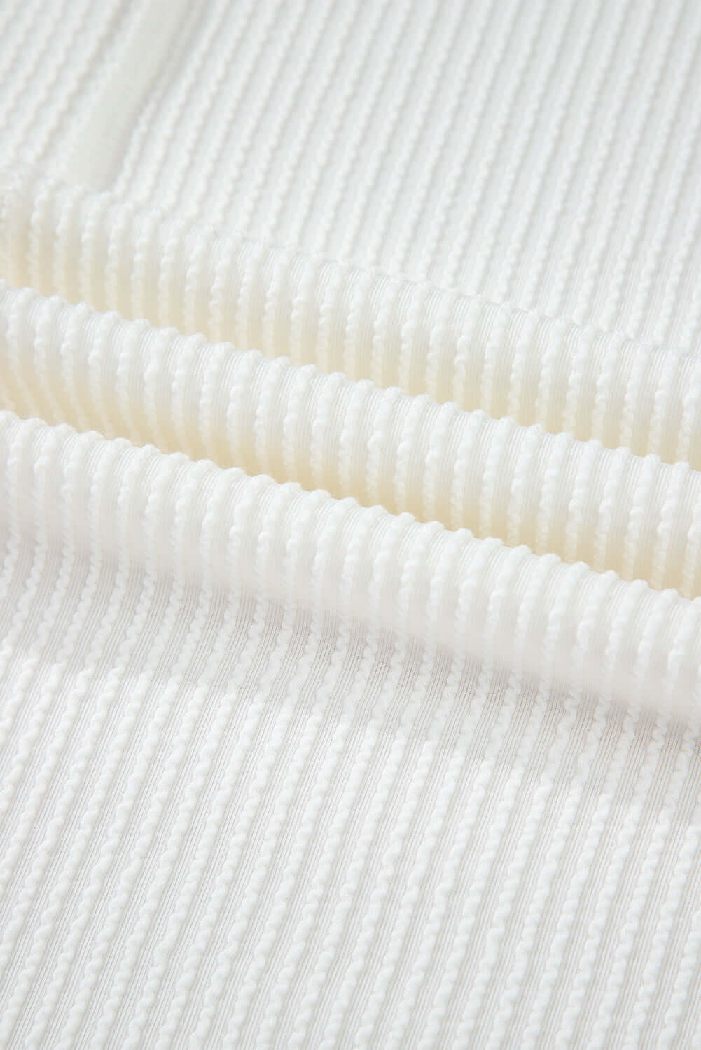 Close-up of soft, lightweight ribbed fabric in a warm ivory hue, ideal for stylish apparel.