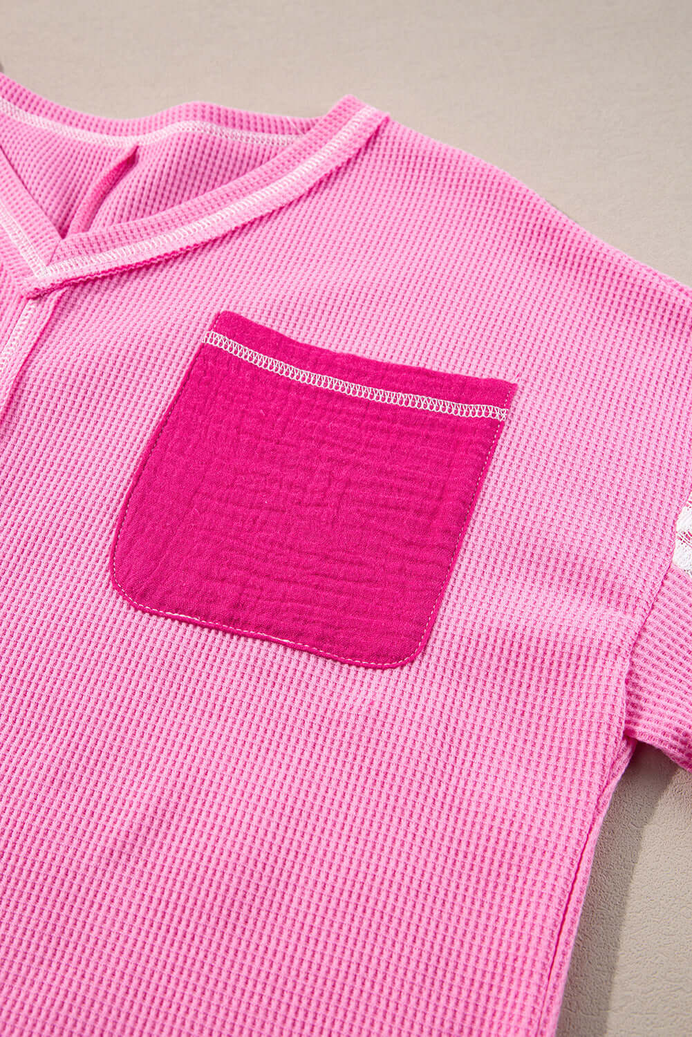 Close-up of pink ribbed top with a contrasting pocket, showcasing soft fabric and modern design details.