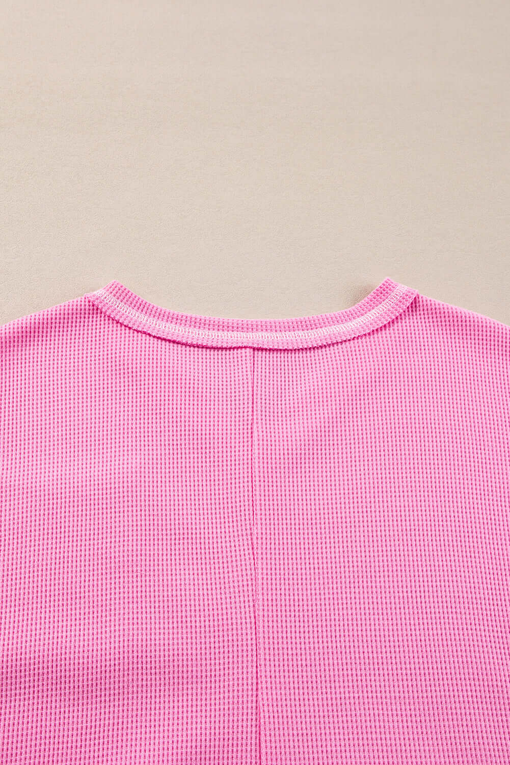 Back view of a vibrant pink ribbed knit top, showcasing its comfortable and stylish design.