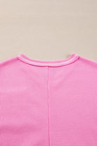 Back view of a vibrant pink ribbed knit top, showcasing its comfortable and stylish design.