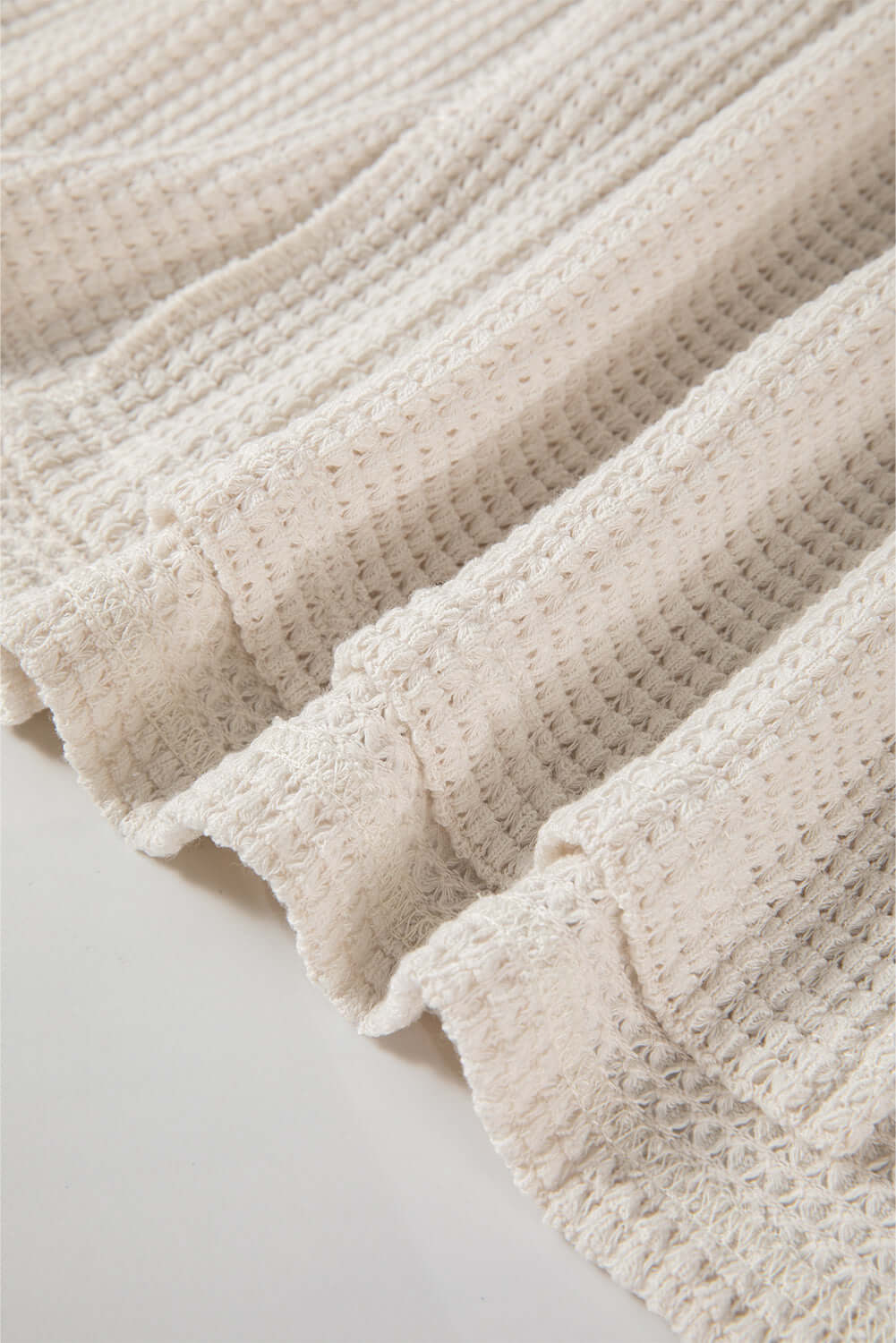 Cream waffle knit fabric texture showcasing detailed pattern and soft material.