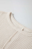 Close-up of a waffle knit texture on a plain top with a round neckline, showcasing stylish stitching detail.