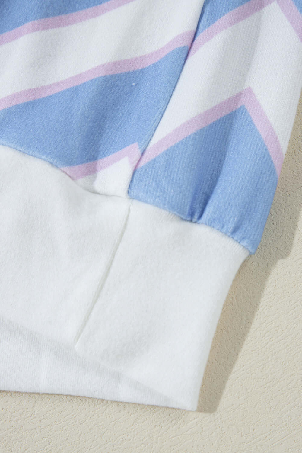 Close-up of the cuff detail of the Chevron Chic top, featuring a zigzag stripe pattern in blue and pink hues.