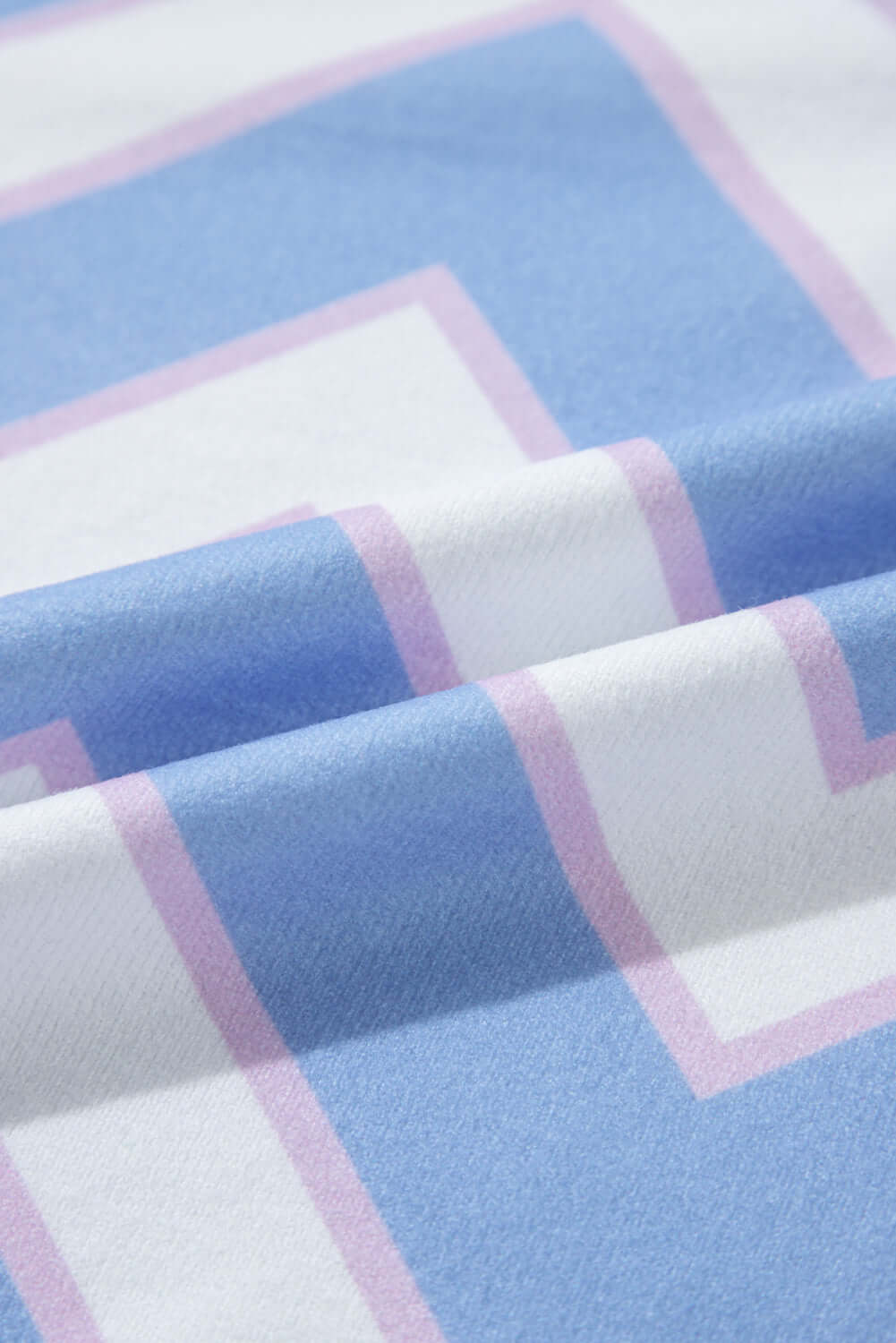 Close-up of fabric featuring a blue and pink chevron pattern, highlighting soft texture and vibrant design.