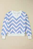 Chevron Chic top in blue with zigzag stripes, relaxed fit, drop shoulder silhouette, and buttoned cuff detail.