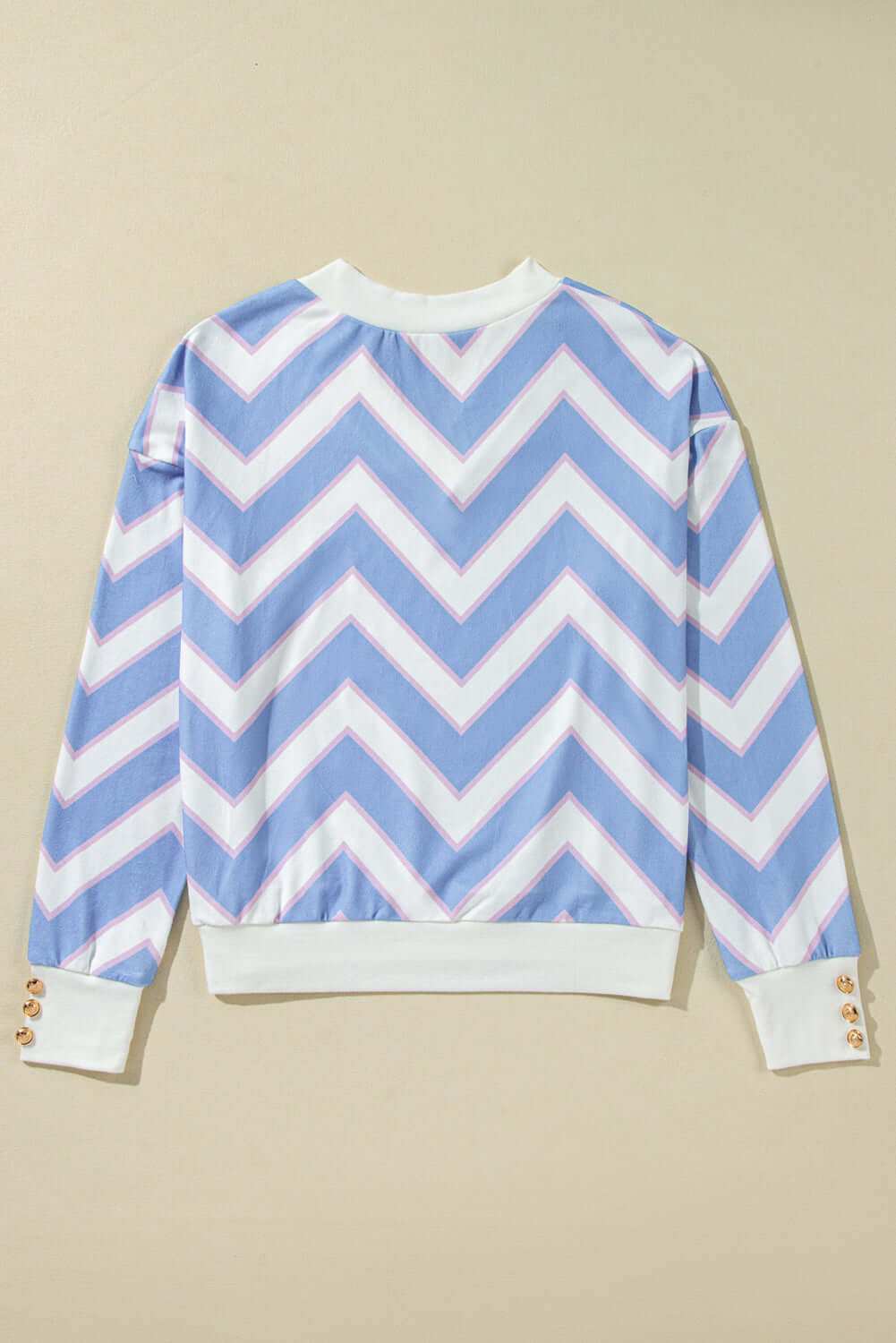 Back view of Chevron Chic top featuring a blue zigzag stripe pattern and stylish buttoned cuff detail.