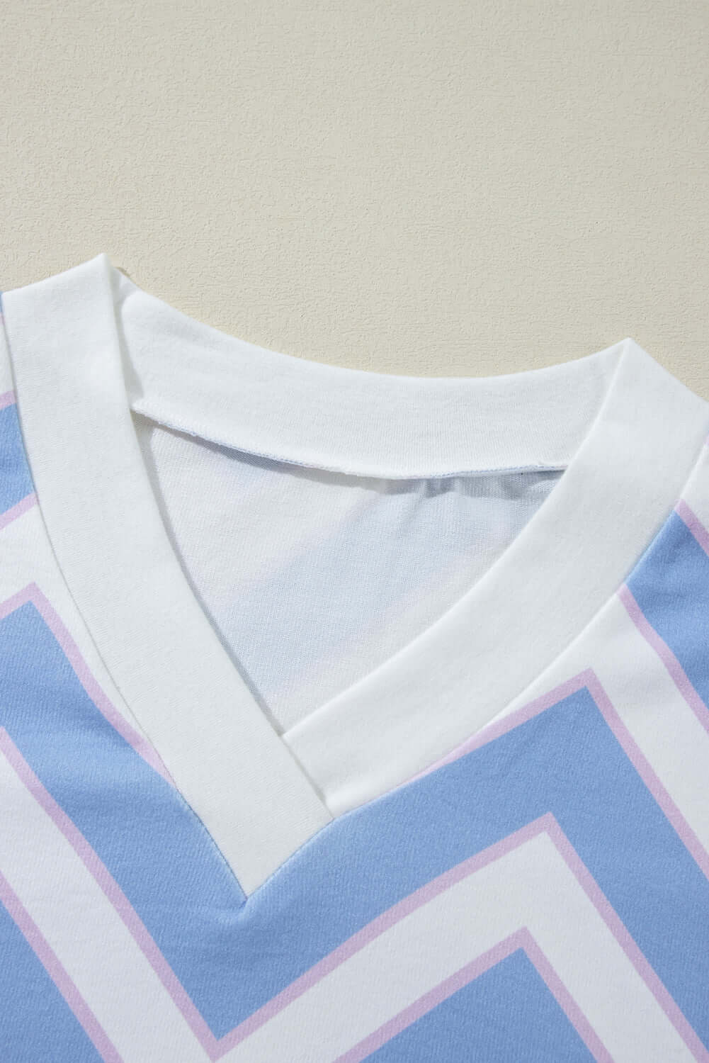 Chevron Chic top featuring a stylish blue and pink zigzag pattern with a modern V-neck design and white collar.