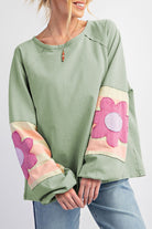 Sage oversized pullover with floral patch sleeves, vintage style, exposed seams, raw cut details, and bubble sleeves.