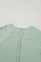 Back view of sage green oversize pullover with exposed seams and raw cut details in a soft fabric blend.