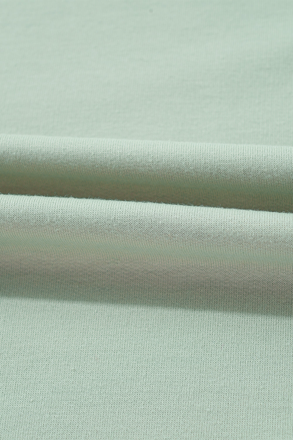 Close-up of sage green A WHOLE MOOD TOP fabric, showcasing soft texture and quality material blend.