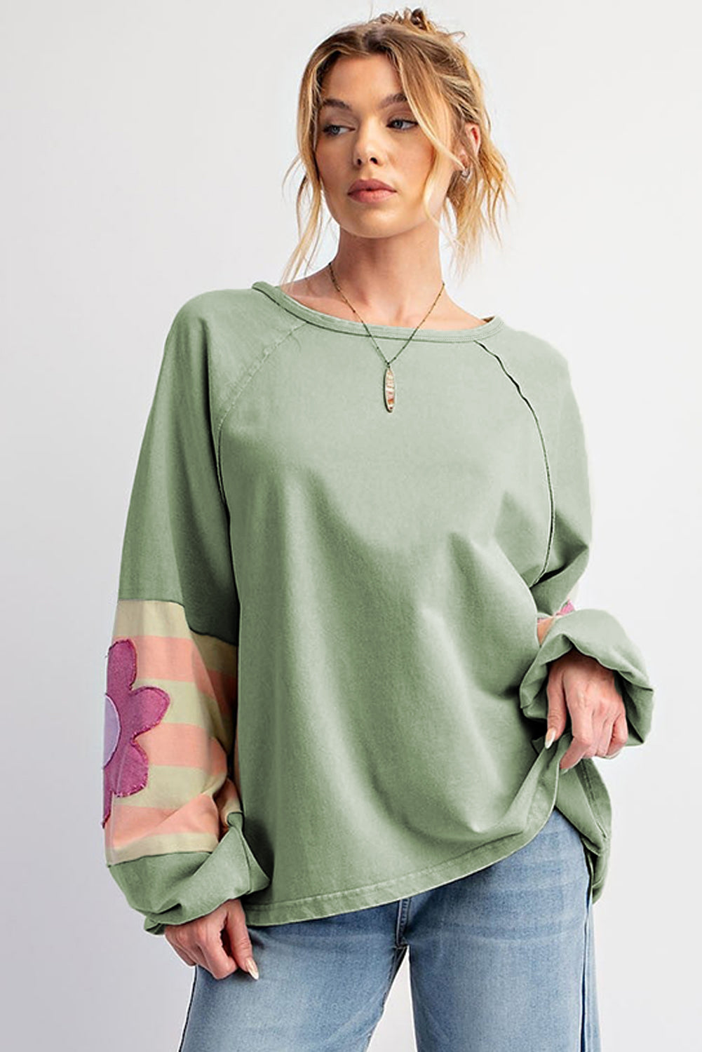 Sage oversized pullover with vintage flair, bubble sleeves, exposed seams, and flower stripe pattern, worn by a woman.