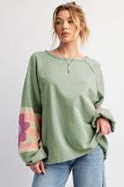 Sage oversized pullover with vintage flair, bubble sleeves, exposed seams, and flower stripe pattern, worn by a woman.