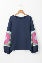 Blue oversized pullover with floral sleeve pattern, bubble sleeves, and raw cut details for a vintage flair.