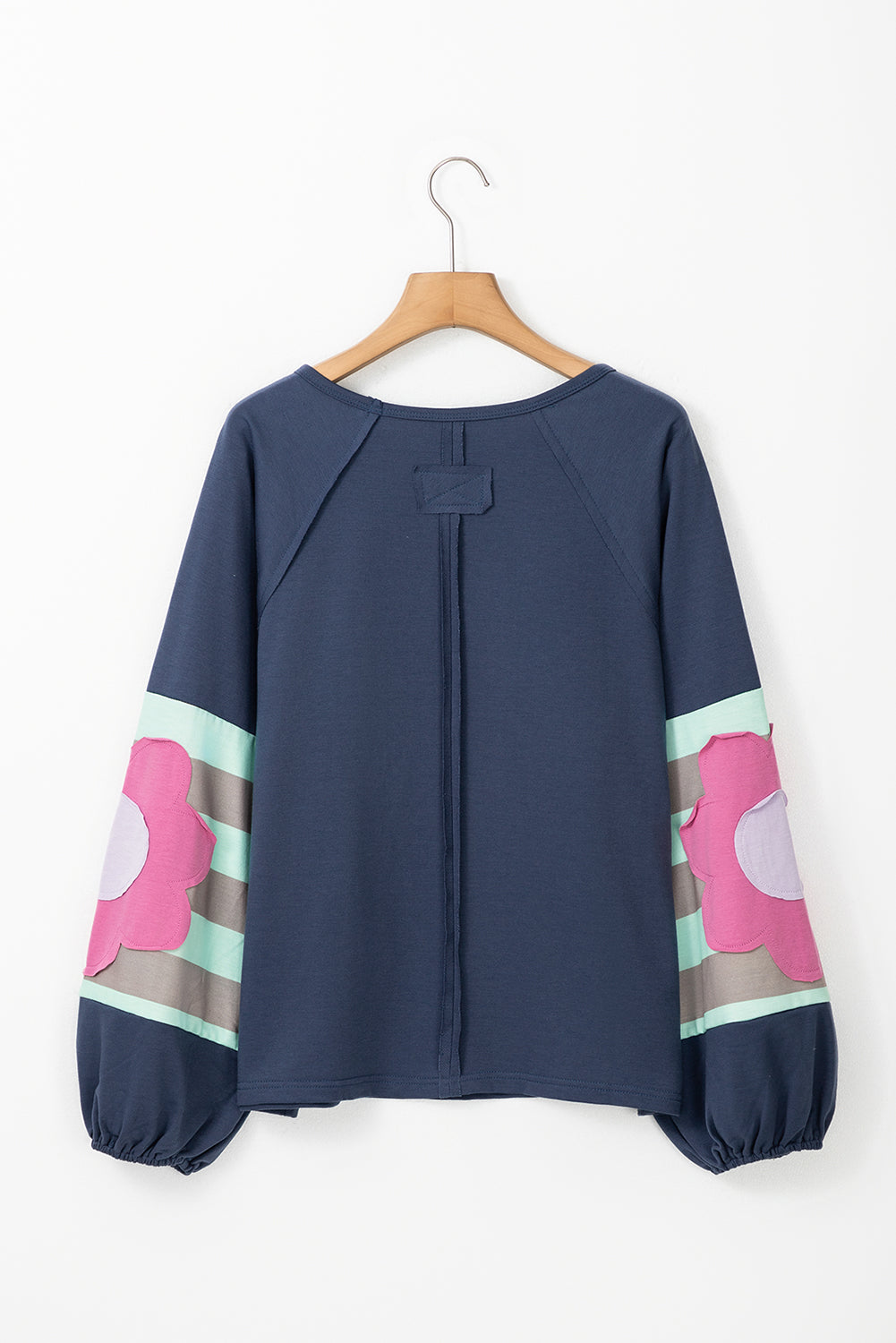 Blue oversized pullover with vintage flair, bubble sleeves featuring pink floral and stripe patterns, exposed seams, and raw cut details.