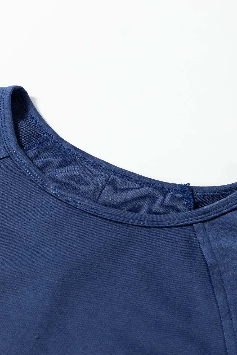 Close-up of blue oversized pullover top with exposed seams and raw cut details.