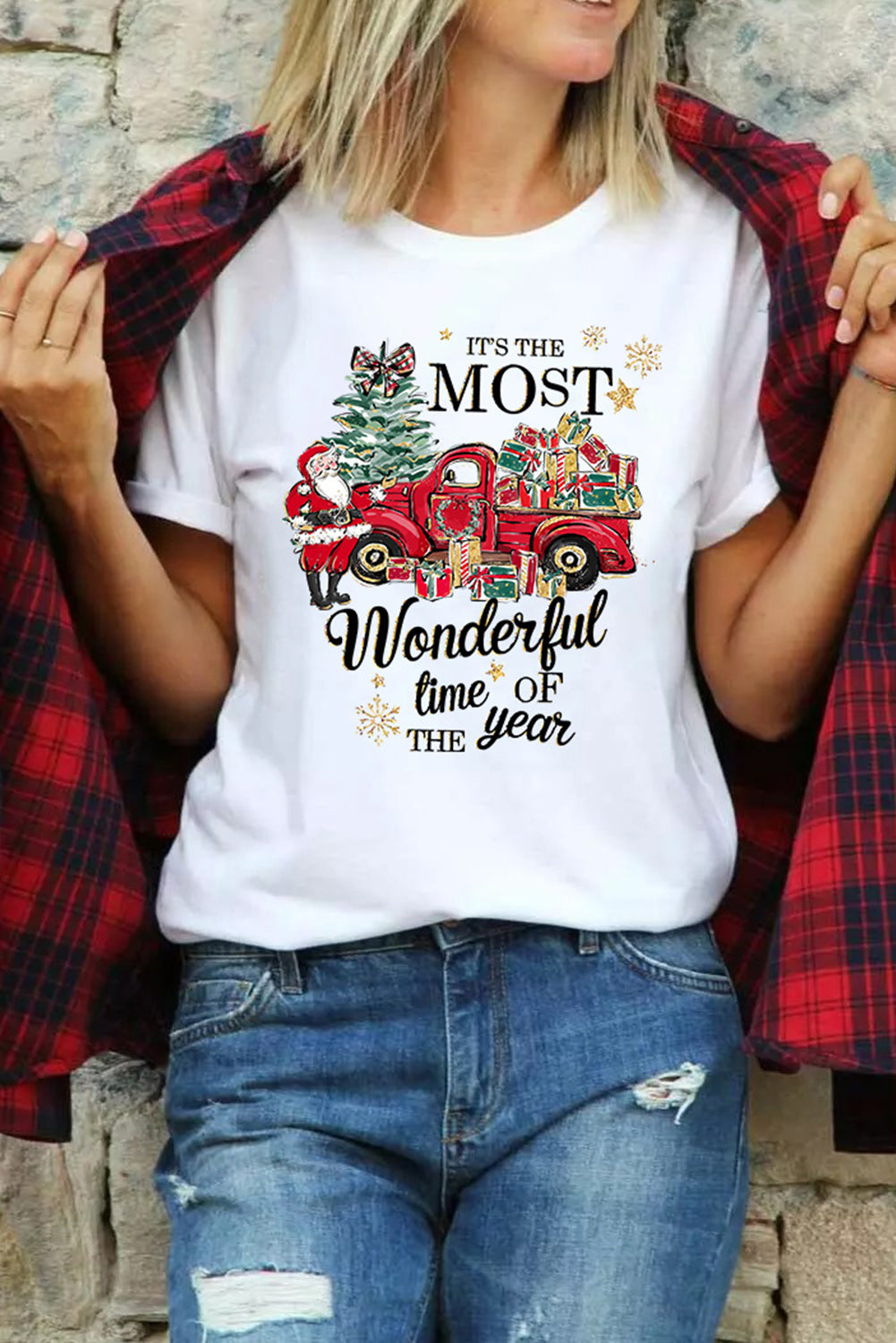 Woman wearing 'Most Wonderful Time' t-shirt with red truck and gifts design; festive holiday apparel with plaid jacket and jeans.