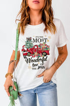 Woman wearing Most Wonderful Time T-shirt with red truck and gifts, holiday design, crew neck, and cuffed sleeves.