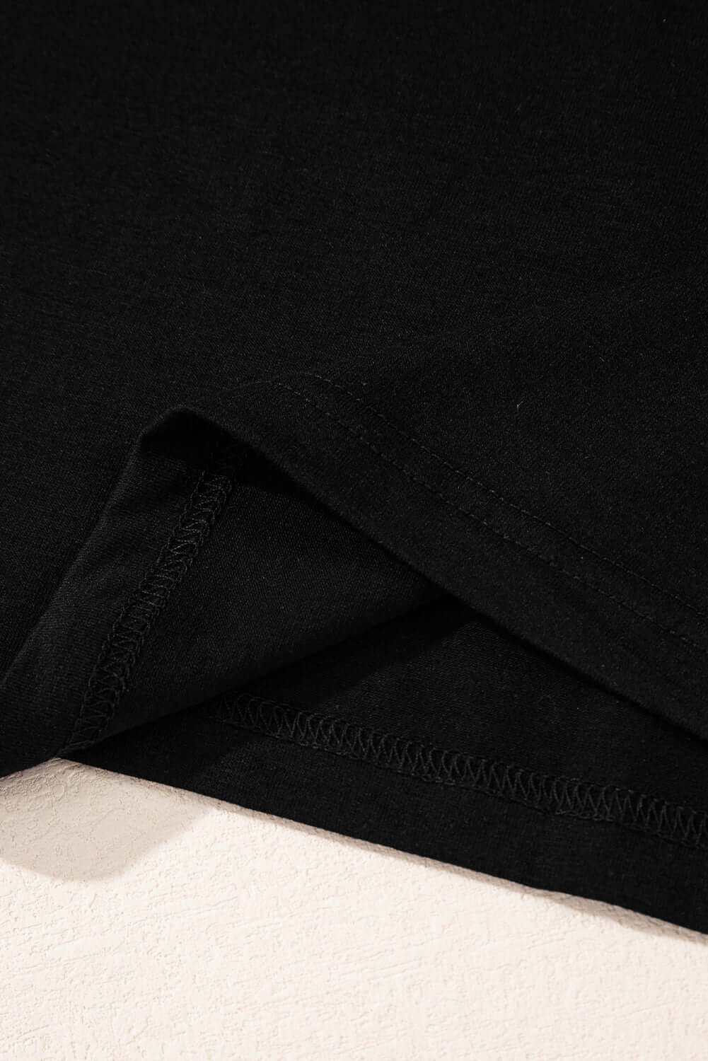 Close-up of black T-shirt fabric and stitching detail showcasing quality craftsmanship and soft texture.