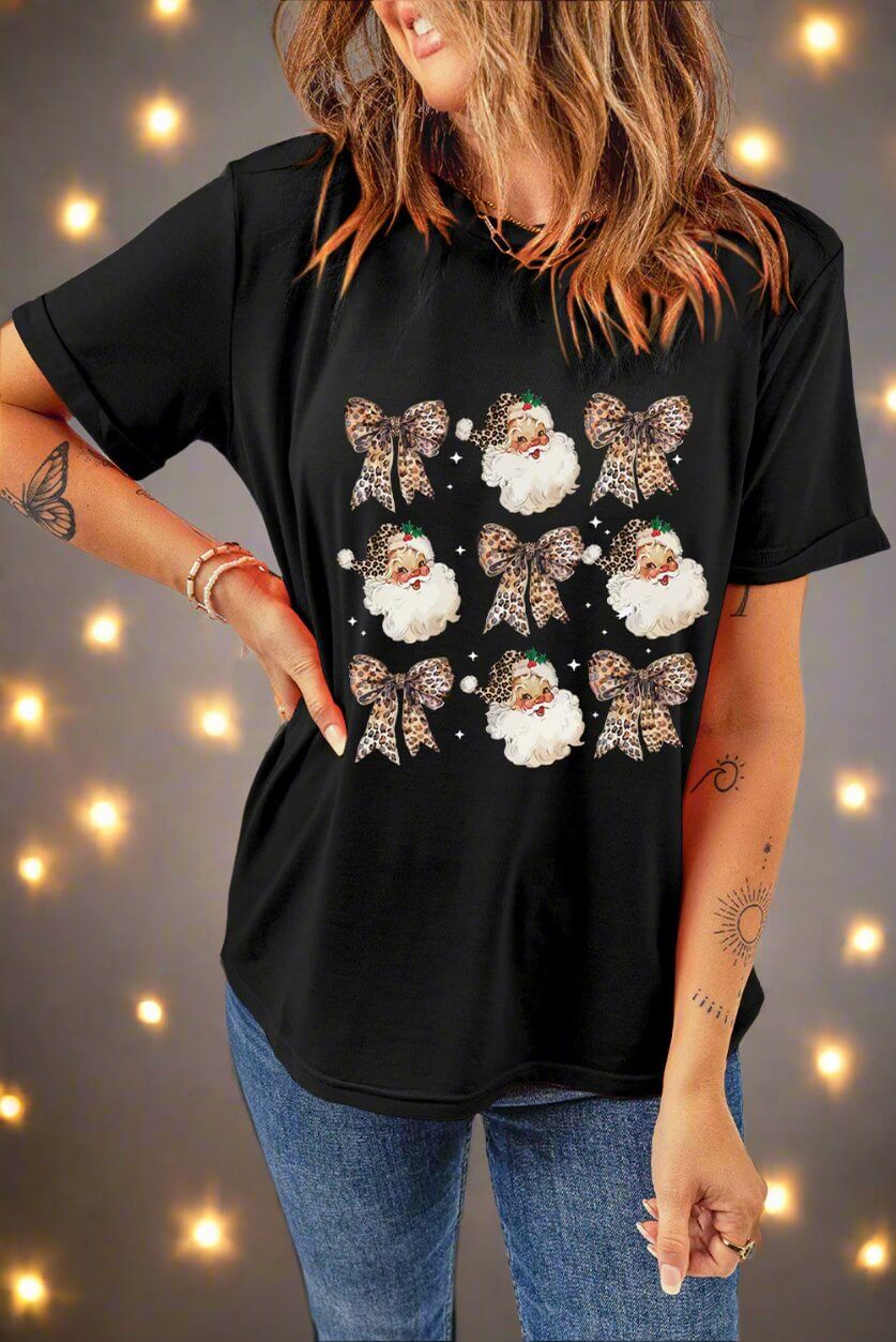 Festive black T-shirt with Santa and leopard print bows, worn with jeans, perfect for a stylish holiday look.