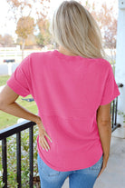 Back view of a woman wearing a striped hot pink knit top, showcasing its relaxed fit and mock neckline.