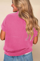Back view of a woman wearing a hot pink color code top with corded knit texture and relaxed fit.