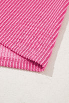 Close-up of hot pink corded knit fabric, showcasing its striped texture and vibrant color pattern.