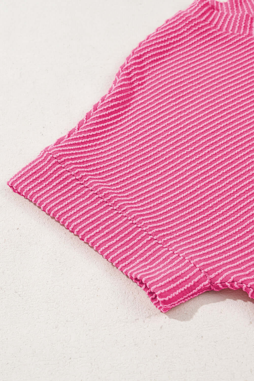 Close-up of hot pink corded knit top showcasing ribbed texture and short sleeves.